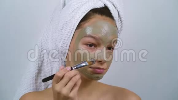 裹着浴巾在脸上涂粘土面膜的少女视频的预览图