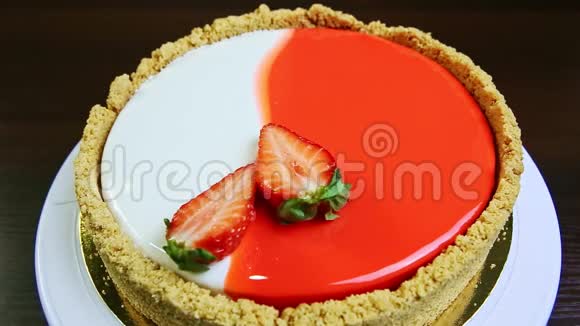 顶部的特写镜头整个圆形釉面芝士蛋糕上面装饰着草莓切片视频的预览图