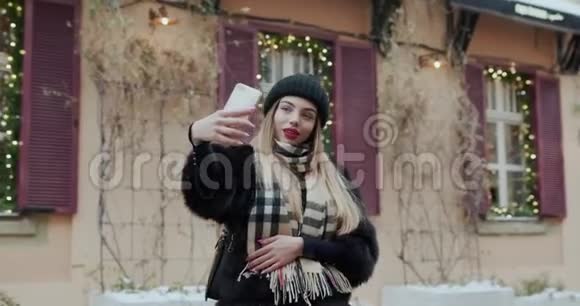 肖像美丽的女孩在街上的智能手机上自拍照片性感女人穿着豪华服装在户外拍照视频的预览图