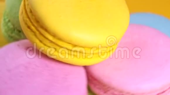 五颜六色的美味杏仁饼在黄色背景上旋转视频的预览图