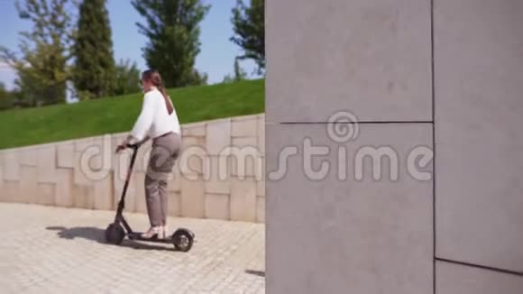 一个女人在公园里用电动滑板车在没有交通堵塞的情况下在城市周围快速移动的新装置视频的预览图