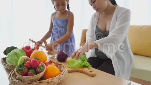 母女俩在家客厅里一起用混合水果和蔬菜做沙拉家庭和人民幸福视频的预览图