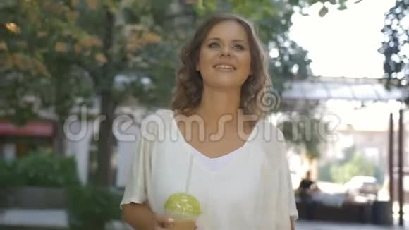 快乐的中年女人在阳光下走在街上手里拿着一个冰沙杯视频的预览图