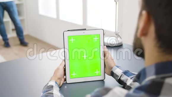在现代明亮的公寓里看绿色屏幕数字平板电脑视频的预览图