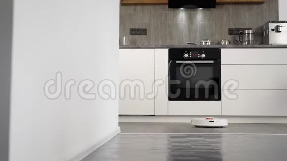 机器人吸尘器正在清洁现代新工作室公寓的地板可以看到厨房视频的预览图