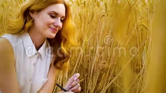 戴着红发的浪漫女孩坐在麦田里视频的预览图