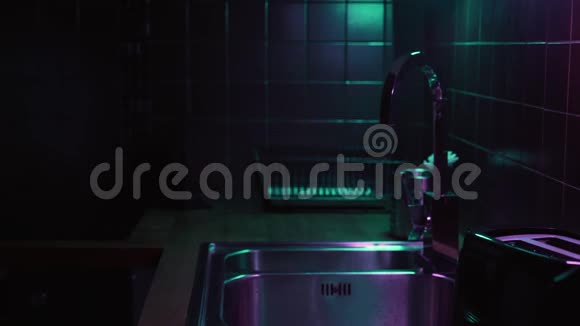女人打开起重机与水在现代厨房与霓虹灯和洗脏玻璃视频的预览图