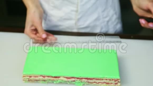 厨师制服的糖果师把尺子放在绿色釉面矩形分层蛋糕旁边视频的预览图