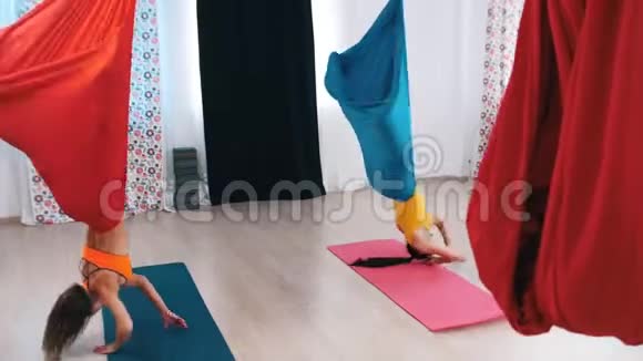 空中瑜伽两个女人倒吊在吊床上旋转视频的预览图