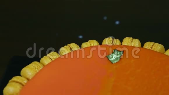 半个装饰着马卡龙的橙色釉面芝士蛋糕的特写全景视频的预览图