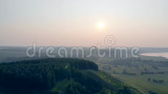 雾中的风景绿树成荫一架滑翔伞飞在上面视频的预览图