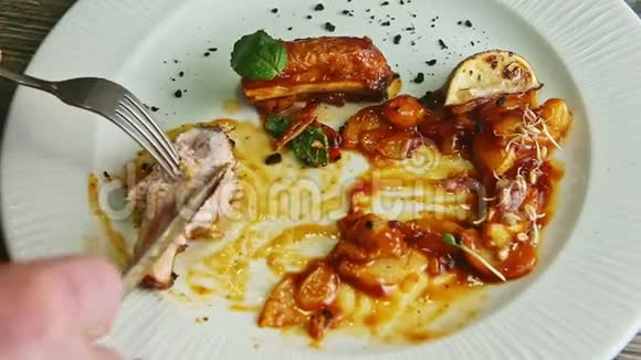 人手用叉子和刀把烤好的肉肋骨切成棕色酱汁视频的预览图