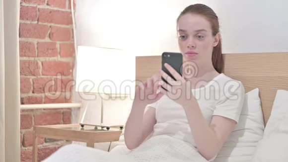 勤劳的红发青年女子在智能手机上失败视频的预览图