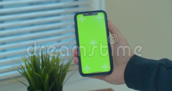 一只手握着一部移动电话手握着一个垂直绿色屏幕的chroma关键智能手机技术视频的预览图