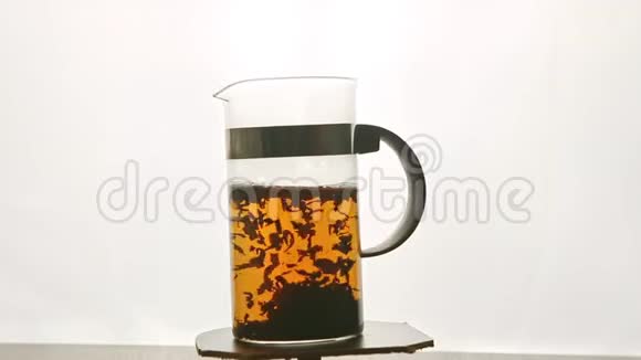 带热茶的高玻璃茶壶在基座上与白色旋转视频的预览图