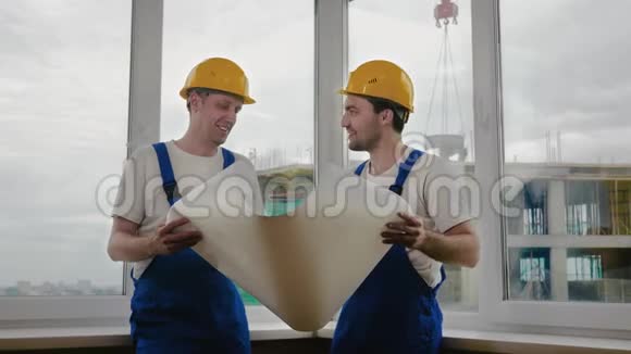 戴头盔的工人看图纸修理视频的预览图