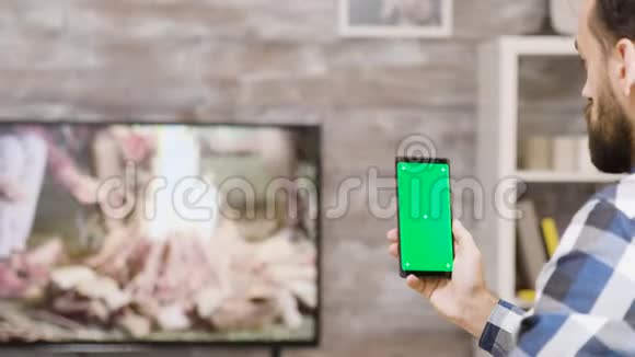 留胡子的人拿着绿色屏幕的电话的背面视频的预览图