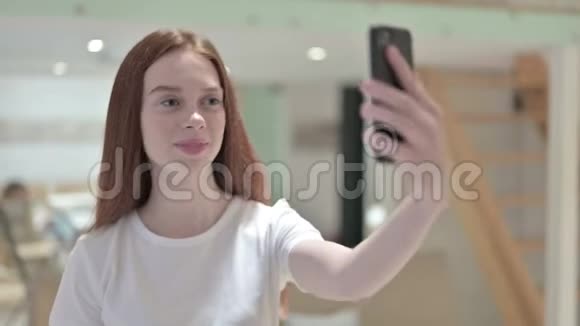 在智能手机上自拍的美丽红头发年轻女人的肖像视频的预览图