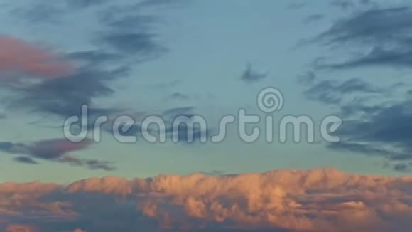 日落时分在蓝天上用蓬松的粉红色云彩从热带景观中缩放视频的预览图