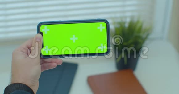 一只手握着一部移动电话手握着一个垂直绿色屏幕的chroma关键智能手机技术视频的预览图