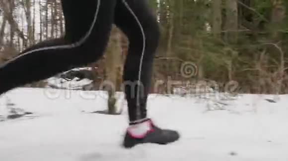 穿着黑色运动紧身衣的女人的腿在雪道上奔跑柔和的焦点视频的预览图