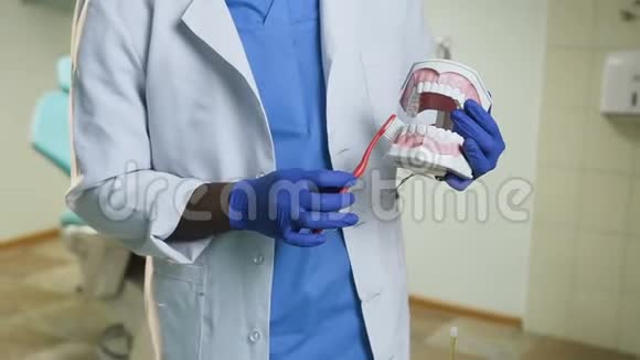 非洲男性牙医展示如何用牙刷在塑料模型上清洁牙齿视频的预览图