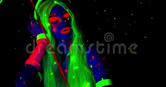 年轻女子绿发发亮微笑着坐在紫外线下视频的预览图