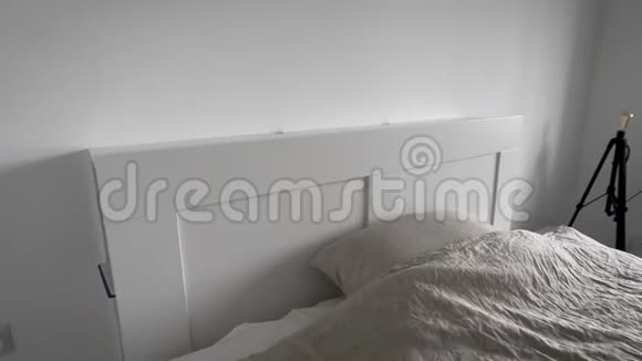 现代卧室的内部一间明亮的房间有白色的墙壁一张宽床有毯子和枕头视频的预览图