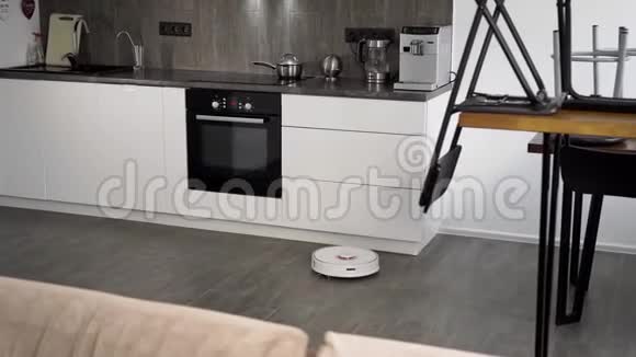 在时尚的现代厨房里打扫卫生自动机器人吸尘器沿着其轨迹移动a的要素视频的预览图