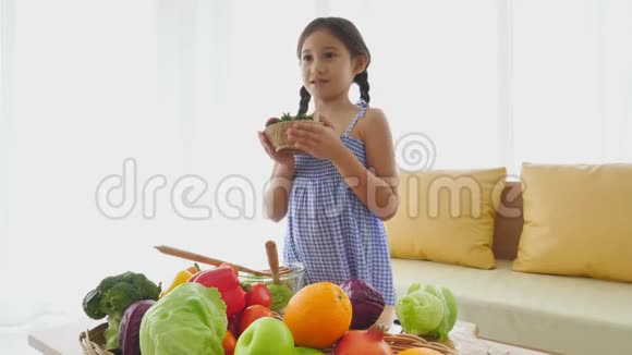 可爱的女孩用混合水果和蔬菜做沙拉并在客厅里向客人介绍家庭和人民幸福视频的预览图