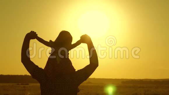 爸爸心爱的孩子在她的怀里跳舞在飞翔笑快乐的婴儿在日落时和他的父亲玩一张剪影视频的预览图