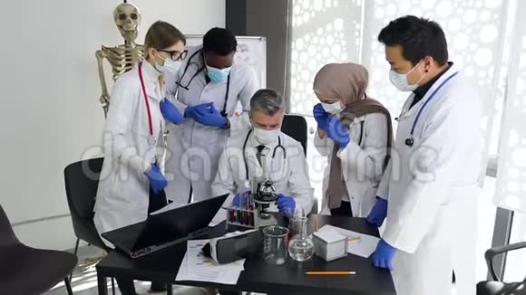 四名戴口罩的有吸引力的多民族男女医生站在他们有经验的女医生周围视频的预览图