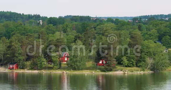 夏季多云天气岛上海岸的许多红色瑞典木制桑拿木屋视频的预览图