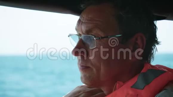 在海上漂浮的船上戴眼镜的渔夫的脸视频的预览图