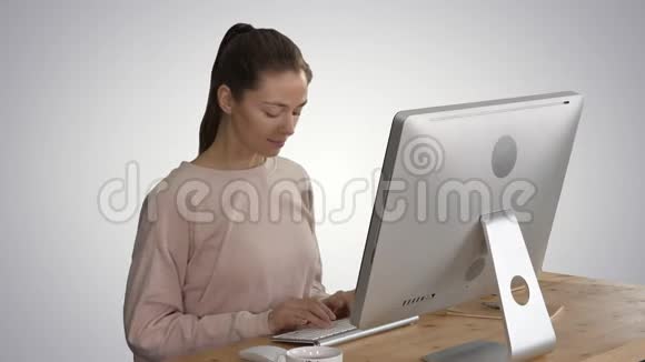 快乐轻松的年轻女子坐在电脑前伸展梯度背景视频的预览图