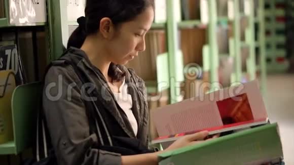 学生女孩坐在书架旁看书视频的预览图