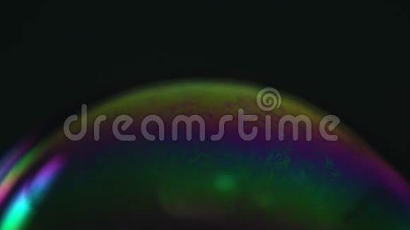 彩虹肥皂泡在黑暗的背景上彩色表面的特写视频的预览图