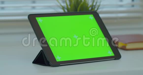 黑色平板电脑在办公桌上绿色屏幕和书籍关闭4k镜头视频的预览图
