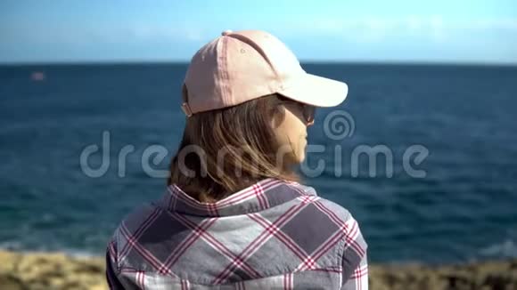 一个年轻的女人正在看海戴帽子的女孩钦佩大自然女人背对着镜头站着视频的预览图