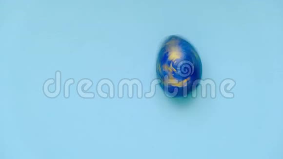 复活节彩蛋在蓝色桌子上旋转鸡蛋时髦的彩色经典蓝色白色和金色复活节快乐最小视频的预览图