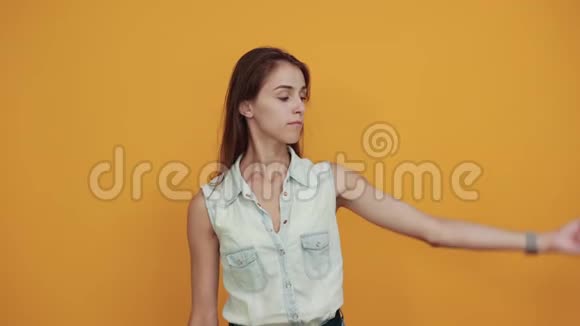 穿着蓝色牛仔衬衫的年轻开朗的女人展现出肌肉看起来很迷人视频的预览图