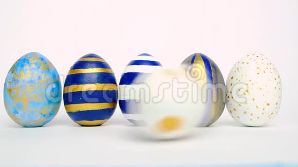 复活节彩蛋在滚动在白色的桌子上互相碰撞鸡蛋时髦的颜色经典的蓝色白色和金色快乐视频的预览图