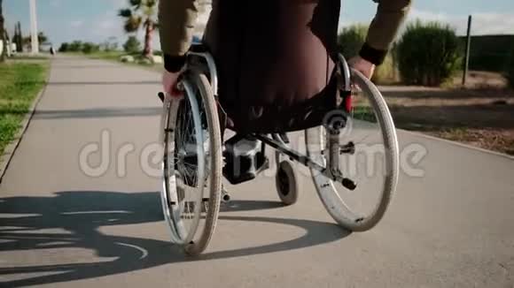在阳光明媚的一天在室外坐轮椅的人行走后景视频的预览图