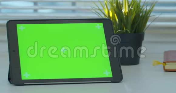 黑色平板电脑在办公桌上绿色屏幕和书籍关闭4k镜头视频的预览图