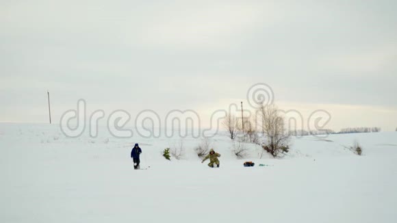 渔民在冬季捕鱼冬天的渔民在多云天气的湖面上视频的预览图
