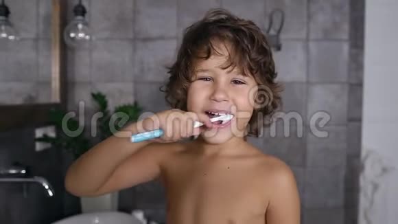 一个可爱英俊的五六岁男孩用白毛巾刷牙的画像视频的预览图