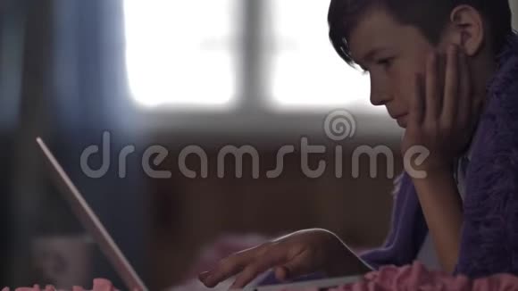 有趣的男孩在家里用笔记本电脑和一杯热咖啡关闭视频的预览图