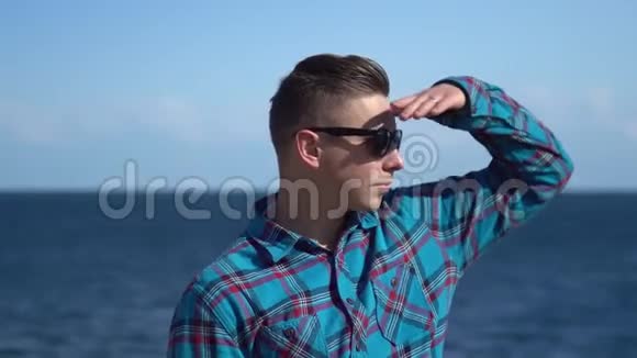 海背景的年轻人阳光明媚的天气里戴太阳镜的人探索周围的自然视频的预览图