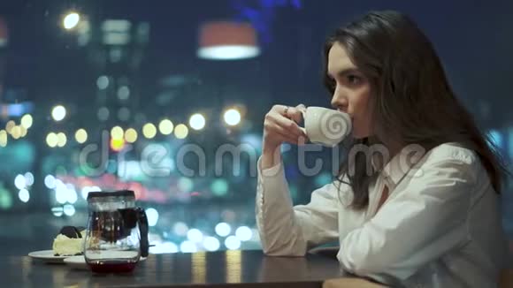 女孩从水壶里倒茶坐在咖啡馆里喝视频的预览图