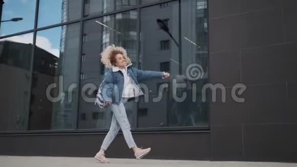 有趣又无忧无虑的女孩在城市里跳舞卷曲的金发女郎疯狂地在户外跳舞视频的预览图
